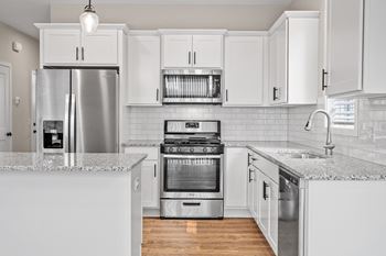 A modern kitchen with white cabinets and stainless steel appliances.